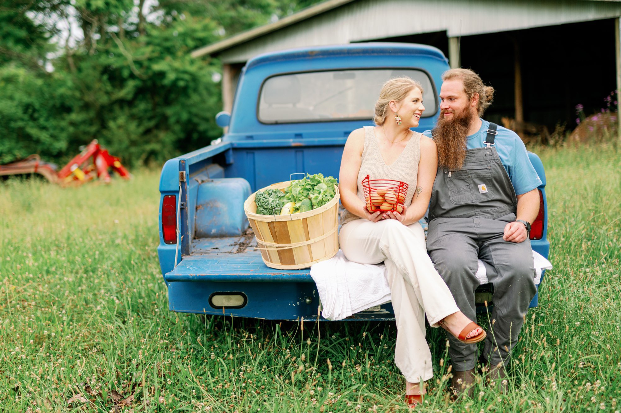 Nick and Dylan Barger on the tailgate of their blue farm truck with a basket of fresh produce